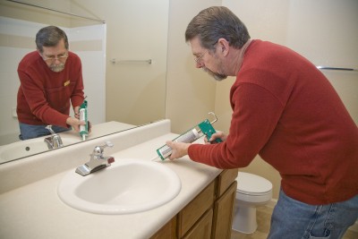 Plumber carefully caulks a sink after a new installation